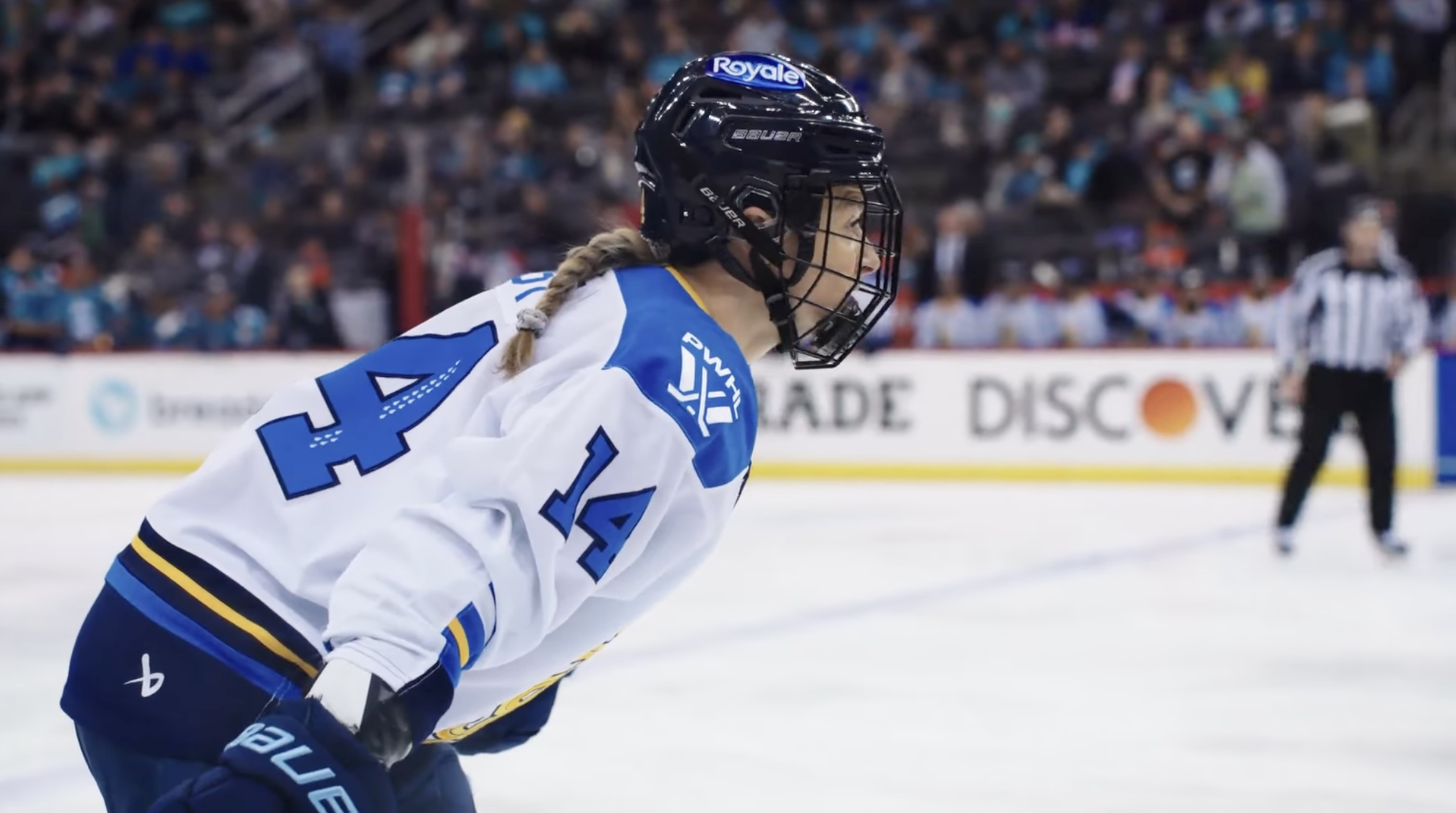 Toronto Sceptres Renata Fast on the ice. The photo is a side profile of her in a white Sceptres jersey with a referee in the background